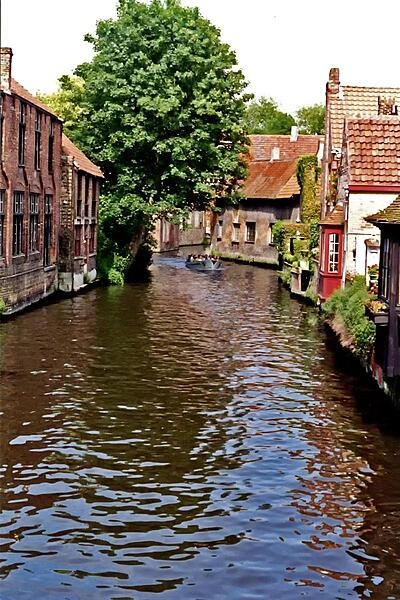 Sightseeing boat on a canal in Bruges (or Brugge), Belgium. The name of the city, which is often called the Venice of the North, is believed to come from the Old Norse word "bryggia," meaning "mooring place." The canals were important in getting trading goods to their destination. Today, they are used exclusively for tourist boats.