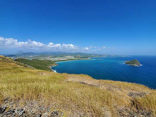 A view from the southern tip of Saint Lucia. The Maria Islands Nature reserve is on the right, the town of Vieux Fort is in the left center, and the Twin Pitons may be seen as bumps on the left horizon.