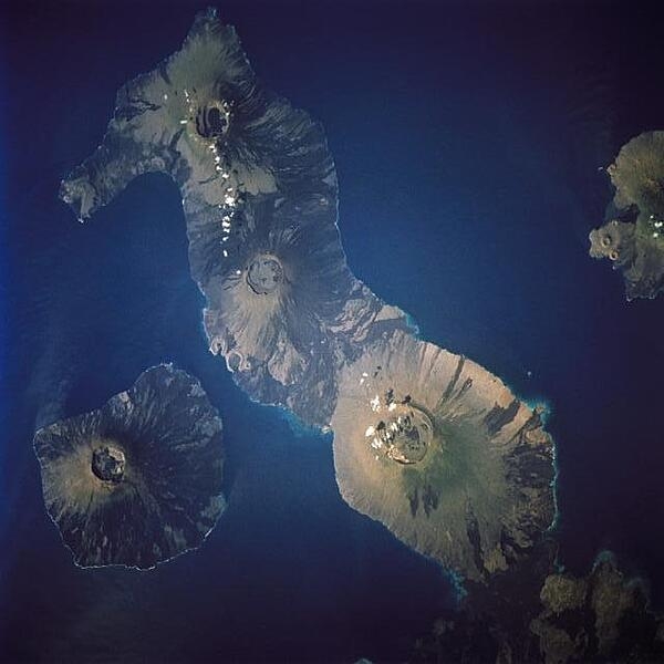 The two westernmost islands of the Galapagos archipelago. The largest of the group, Isabela, stretches across most of the frame. It was created from the merger of six shield volcanoes, several of which are visible in this view. The northernmost and highest, Volcano Wolf (1,707 m or 5,600 ft), lies directly on the equator. The smaller island of Fernandina displays a single volcanic cone. Image courtesy of NASA.