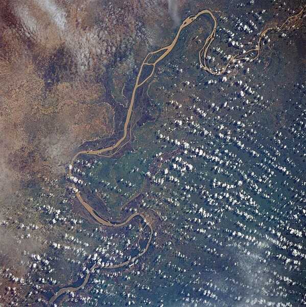 A satellite view of the Gambia River, from Georgetown in the upper right corner of the photograph downstream to Mansa Konko, where it becomes an estuary about 100 km (60 mi) above Banjul, the capital of The Gambia. The river is heavily silted from rain originating in the highlands of Guinea. Image courtesy of NASA.