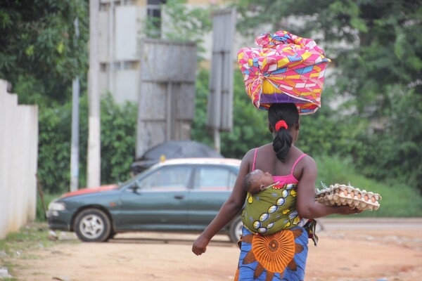 A woman carrying eggs and a baby in Abidjan, Côte d'Ivoire.