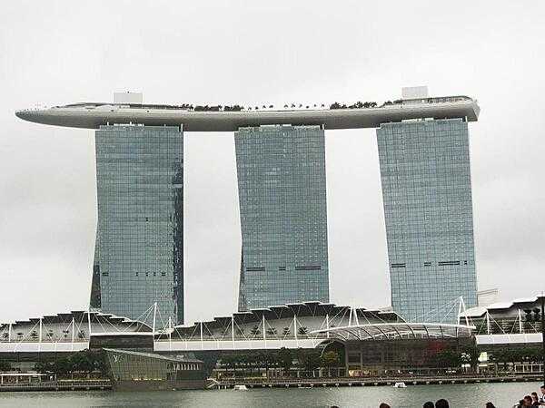 View of the Marina Bay Sands complex in Singapore that opened in 2010 and has since become a city landmark. The three 55-story towers contain hotel rooms. The upper level Sky Park, built to resemble a ship, has the world&apos;s longest elevated swimming pool, restaurants, gardens, and a public observation deck. The integrated resort also includes an adjacent ArtScience Museum, a casino, and a convention center.