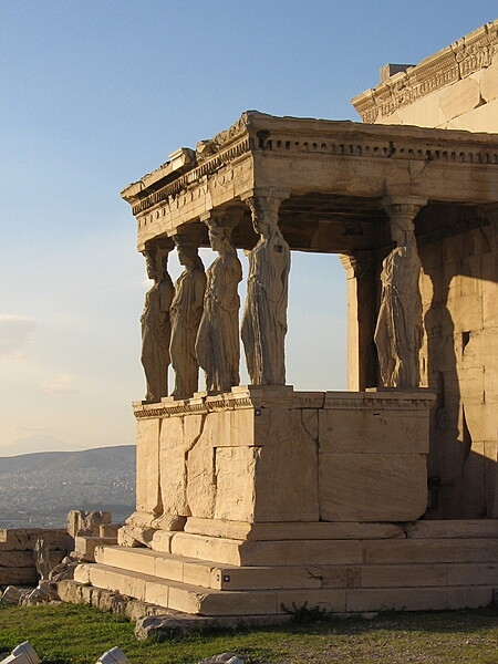 The south side of the Erechtheion with the "Porch of the Maidens," composed of six draped female figures (caryatids) as supporting columns. One of the six figures was removed in the early 19th century and is now in the British Museum in London; it was replaced by a copy. The Acropolis Museum in Athens, Greece, holds the remaining original five figures, which have been replaced onsite by replicas.