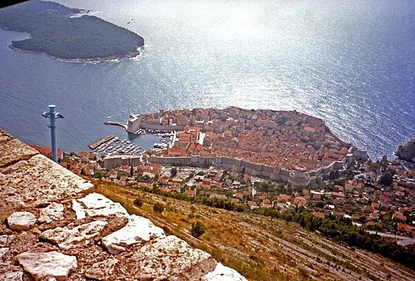 From a cliff overview, one can see the enormous walls and large harbor of old Dubrovnik in Croatia.