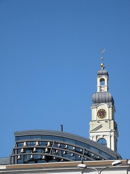 The bells in the foreground were originally cast in the 13th century but were remounted on the roof of the Riga City Council (Town Hall) building in the late 20th century. The modern carillon forms a striking contrast to the Town Hall&apos;s 18th century clock tower. The bells chime every hour on the hour.