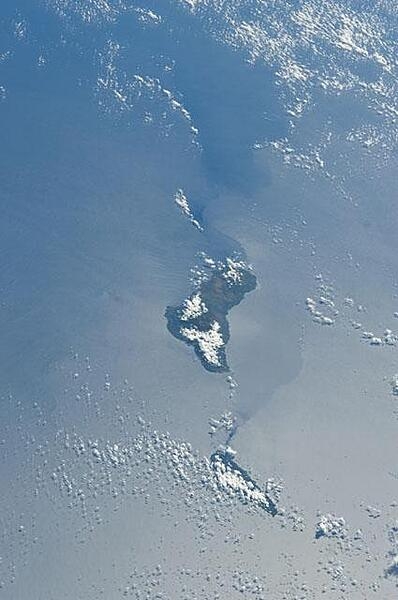 Grande Comore, part of the Comoros archipelago, appears in the center of this view with Moheli (mostly cloud-covered) toward the bottom. The silvery surface of the Mozambique Channel is due to sun glint. Photo courtesy of NASA.