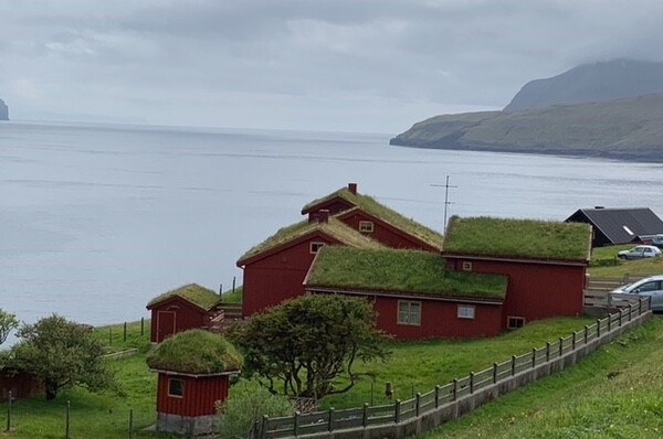 The Faroe Islands are an archipelago between the Norwegian Sea and the North Atlantic Ocean. The terrain is rugged, and the climate is subpolar oceanic, with windy, wet, cloudy, and cool weather. Temperatures average above freezing throughout the year, hovering between 12 °C (54 °F) in summer and 5 °C (41 °F) in winter. Settlers introduced grass roofs to their shelters as an effective protection from the rain and cold.