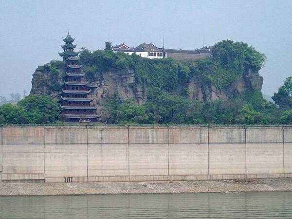 Shibaozhai is a steep, craggy hill on the Yangtze River, in Zhong county, Chongqing, China. A temple at the crest of the 220 m (722 ft) hill was built in the 18th century. A nine-story wooden pagoda was constructed in the 1819 to help pilgrims reach the top of the hill, with three more stories added in 1956.  A coffer dam protects the site from higher river waters -- the result of the Three Gorges Dam.