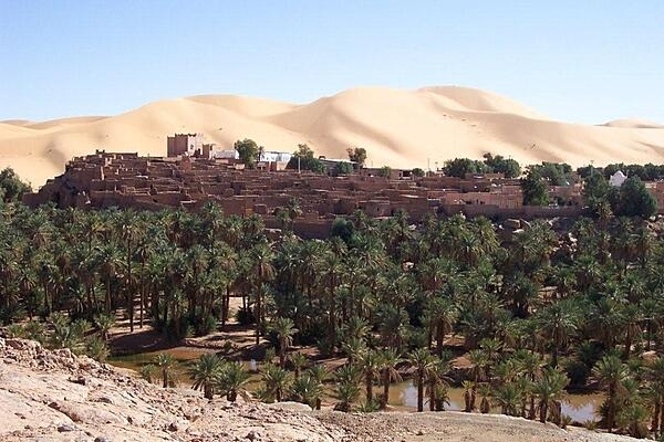 Mountains of sand loom over the oasis village of Taghit in the Sahara.