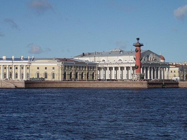 The Old Saint Petersburg Stock Exchange (white building) and one of its flanking Rostral Columns overlooking the inner harbor of the city.