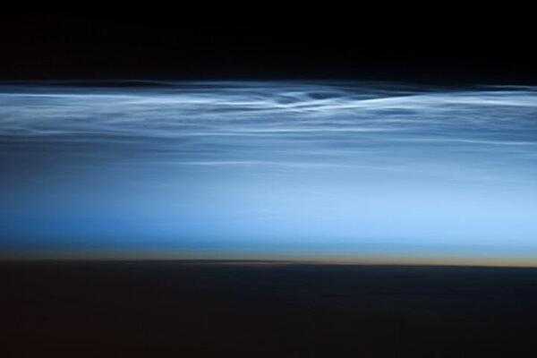 Polar mesospheric clouds - also known as noctilucent or &quot;night shining&quot; clouds - form between 76 to 85 km (47 to 53 mi) above the Earth&apos;s surface, near the boundary of the mesosphere and thermosphere, a region known as the mesopause. At these altitudes, water vapor can freeze into clouds of ice crystals. When the sun is below the horizon and the ground is in darkness, these high clouds may still be illuminated, lending them their ethereal, &quot;night shining&quot; qualities.

Polar mesospheric clouds have been observed from all human vantage points in both the Northern and Southern Hemispheres - from the surface, in aircraft, and from spacecraft - and tend to be most visible during the late spring and early summer. Image courtesy of NASA.