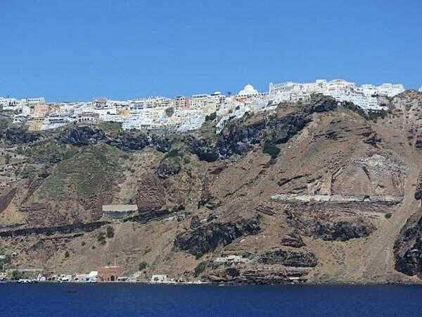 Houses perched on top of 300 m (980 ft) cliffs in the city of Fira on Santorini (Thera) Island in the Mediterranean Sea. Fira is the principal city on the island, and Santorini Island is the southernmost of the Greek Cyclades.