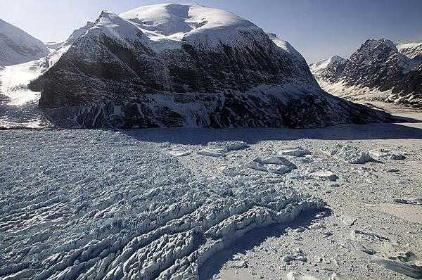 Pictured is the calving front of Kangerdlugssup Glacier in central west Greenland, where large chunks of ice break off from the glaciers to form icebergs. Several large icebergs in the fjord are shown here, surrounded by the dense mixture of iceberg bits and floating sea ice that is known as the “mélange.” Credit: NASA/Michael Studinger.