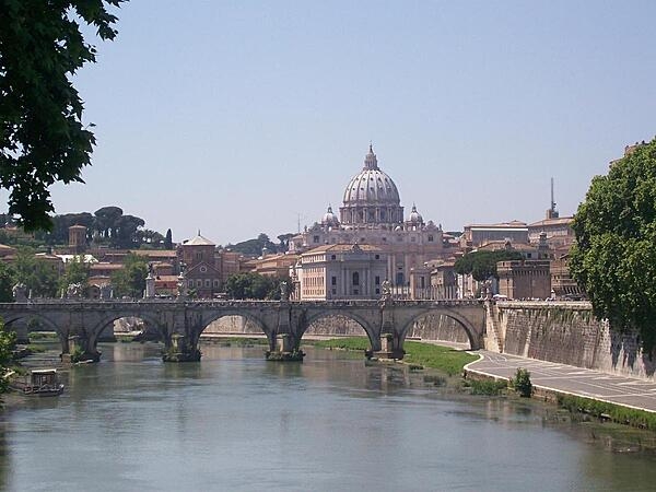 The Vittorio Emanuele Bridge over the Tiber River in Rome, Italy, with Vatican City in the background. The bridge was completed in 1911.